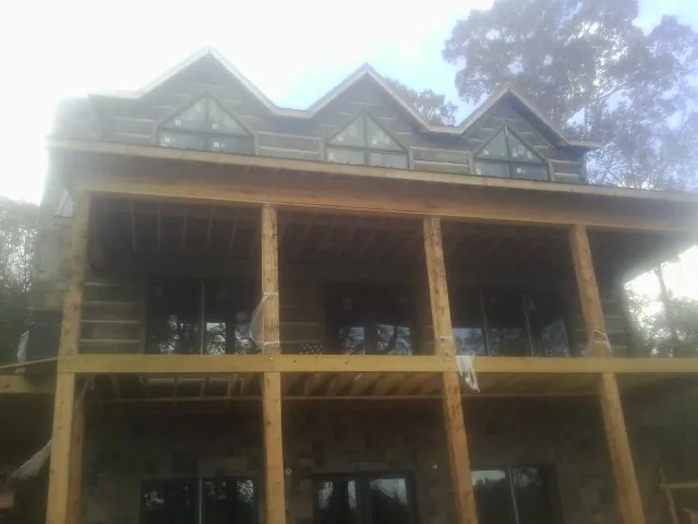 Dormers and porch framing on a large log home under construction — Roof Coating work by our crew in Hubbardston