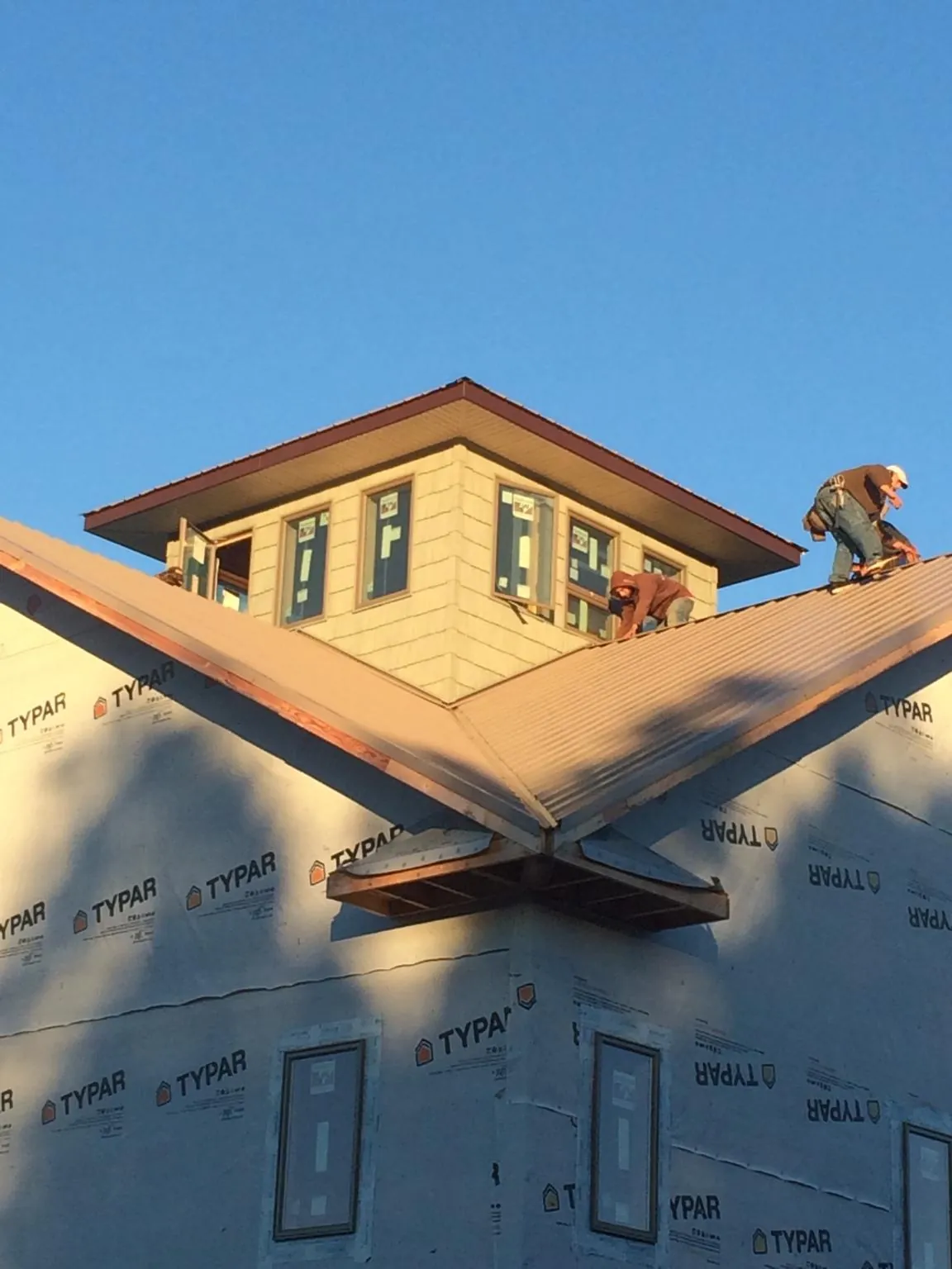 Roofers working around a rooftop cupola on a new metal roof at sunset — Roof Waterproofing in Hubbardston by Roofing Brothers